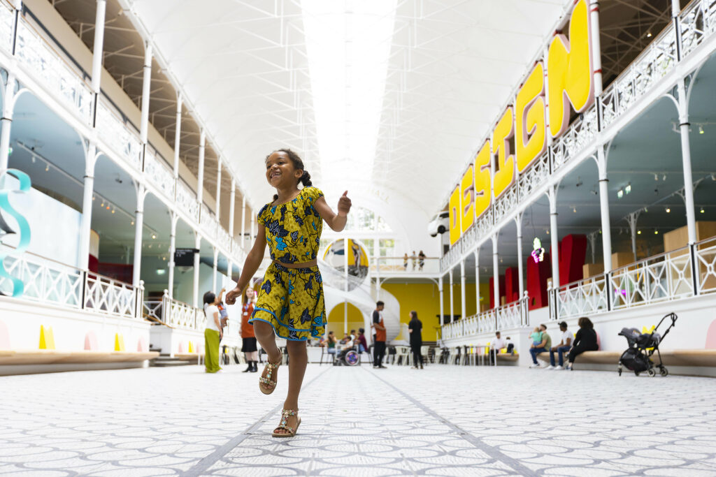Young girl in yellow dress running through the Town Square atrium of Young V&A Museum